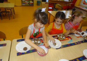 Dwie dziewczynki obtaczają kule czekoladowe w wiórkach kokosowych.